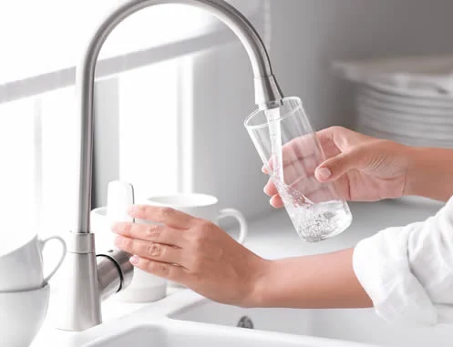Faucet / Tap running a glass of pure clean fresh water in kitchen. Domestic water purification.